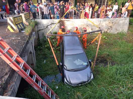 Petugas mengevakuasi mobil yang terjun ke parit